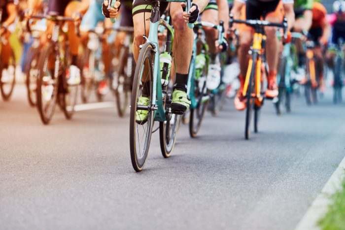 A large group of cyclists racing through a street.