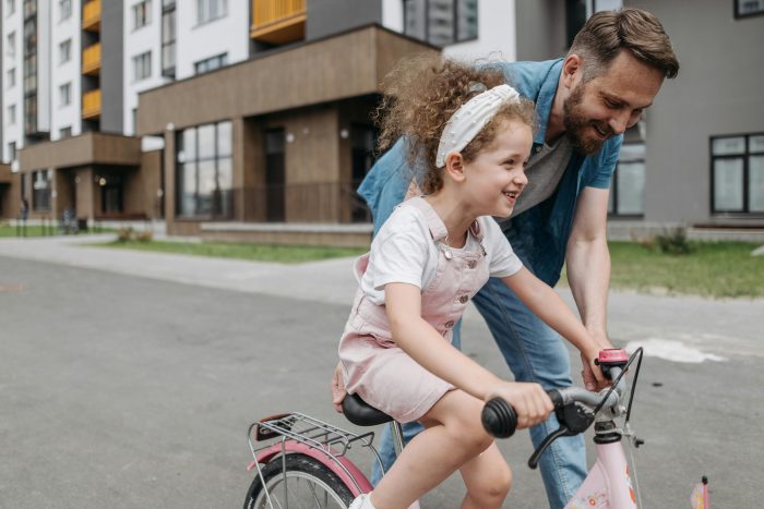 A father helping his daughter learn to ride a bike