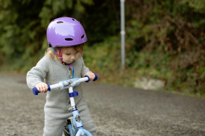 A small child riding a bike with a helmet on