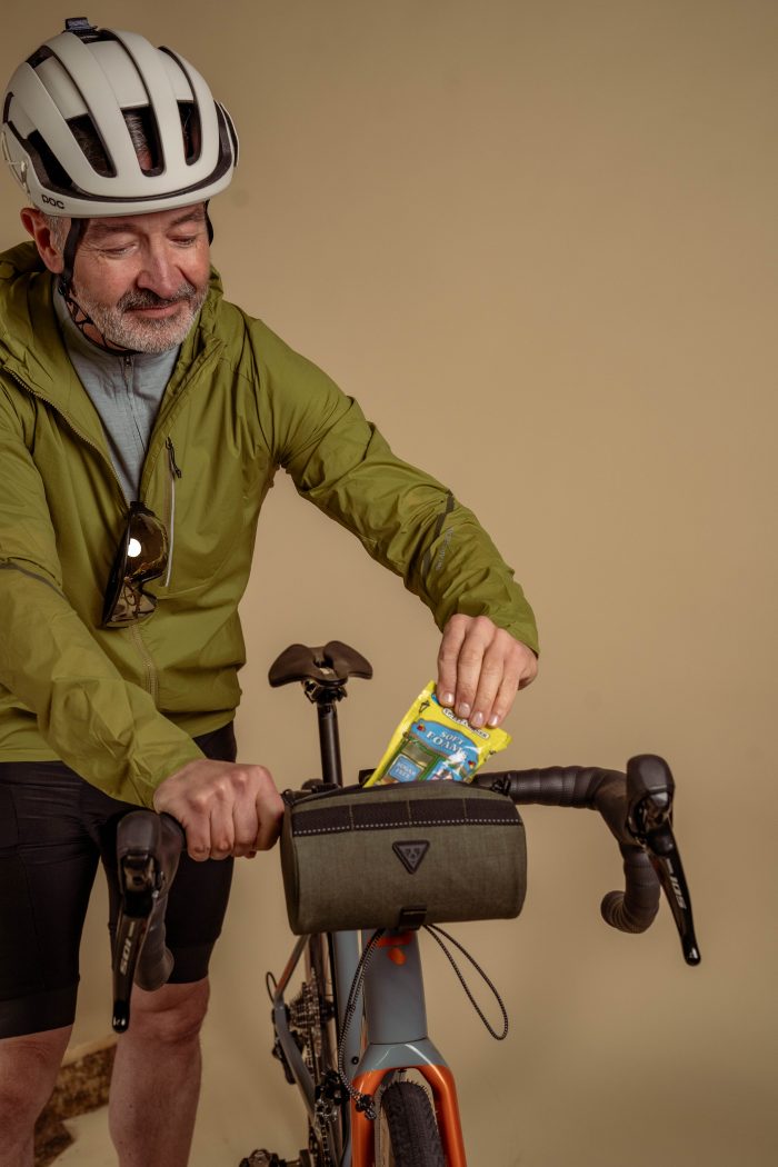 A cyclist packing his handle bar bag for the journey.