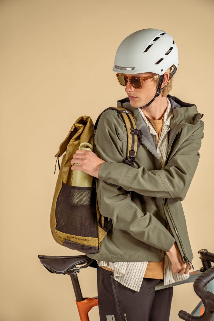 A cyclist wearing smart casual clothes and a rucksack.